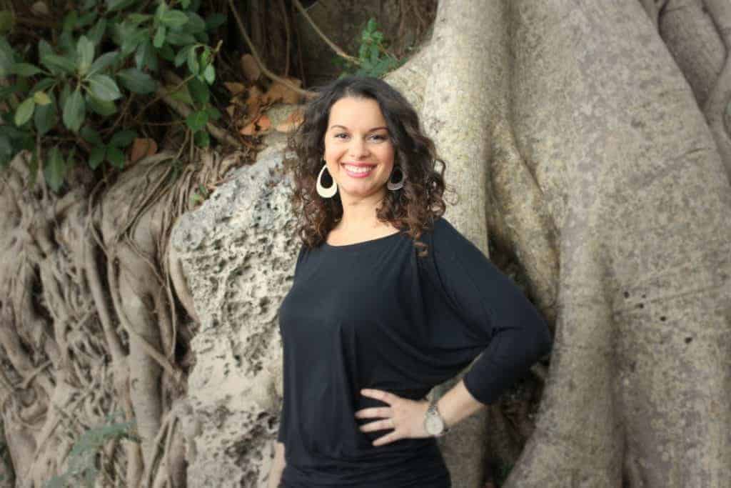 Delilah Orpi the Holistic Enchilada natural beauty curly girl clean living blogger writer curl consultant smiling hand on hip in front of tree roots
