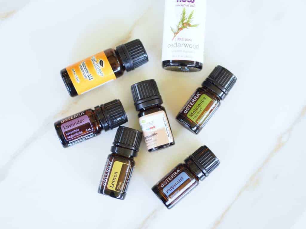 Seven glass bottles of essential oil  beginner's guide to essential oils laying flat on a counter