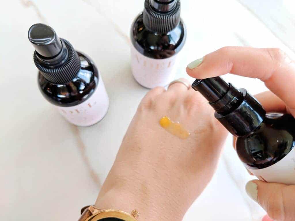 Delilah Orpi testing a'del skincare Luxury Skincare Set step 3 moisturize on the back of her hand with two other glass bottles in the background
