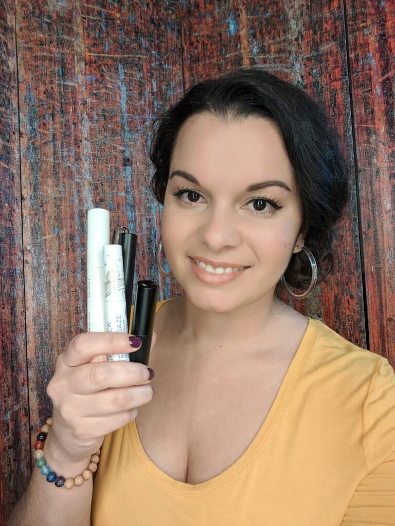 Delilah's holding affordable natural and organic mascaras in her hand smiling