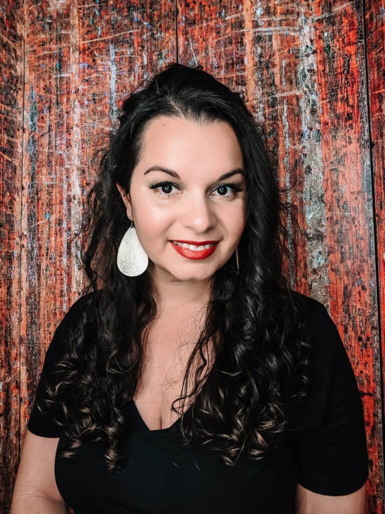 Woman with curly hair pinned back on one side smiling with red lipstick