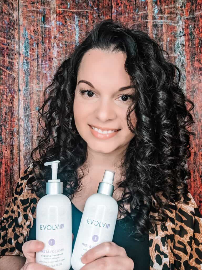Delilah holding two of her top curly girl approved products for 2020 from the EVOLVh brand.