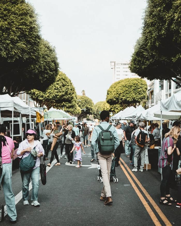 A crowd enjoying a clean and green farmer's market on a beautiful day