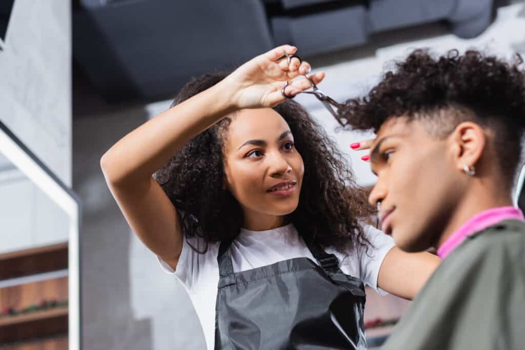 female stylist is cutting a man's curly hair in a salon