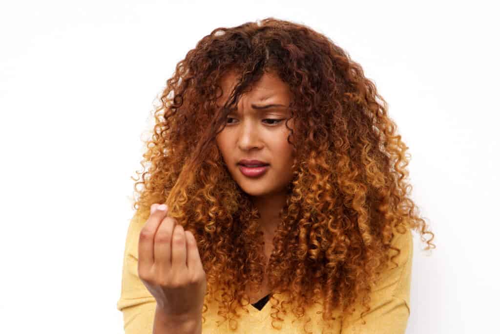 unhappy young woman with dry hair that needs a chelating shampoo