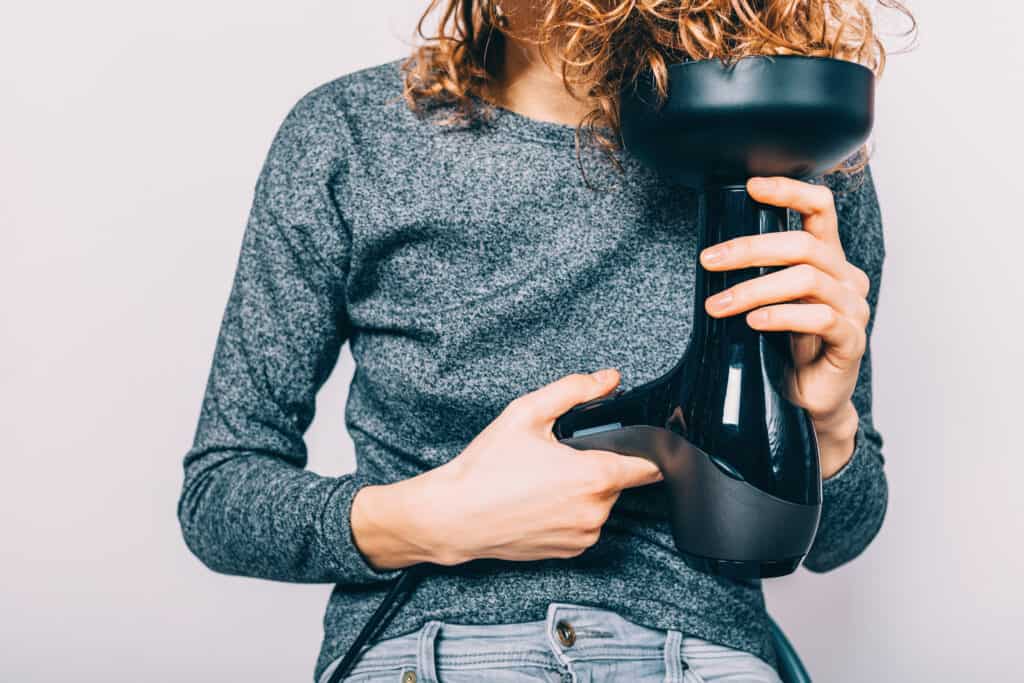 woman showing how to use a diffuser on curly hair