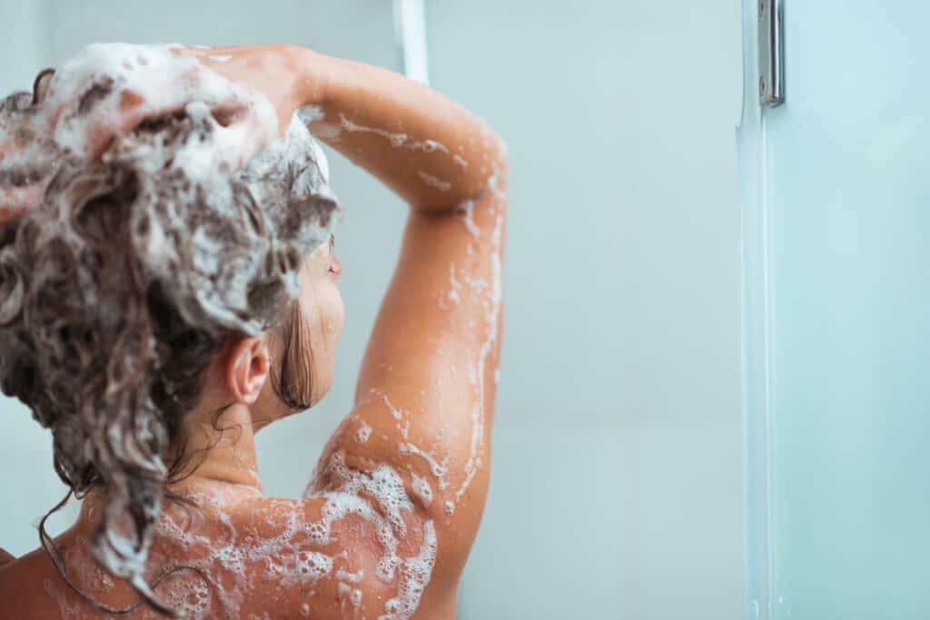 woman shampooing hair with coconut free shampoo