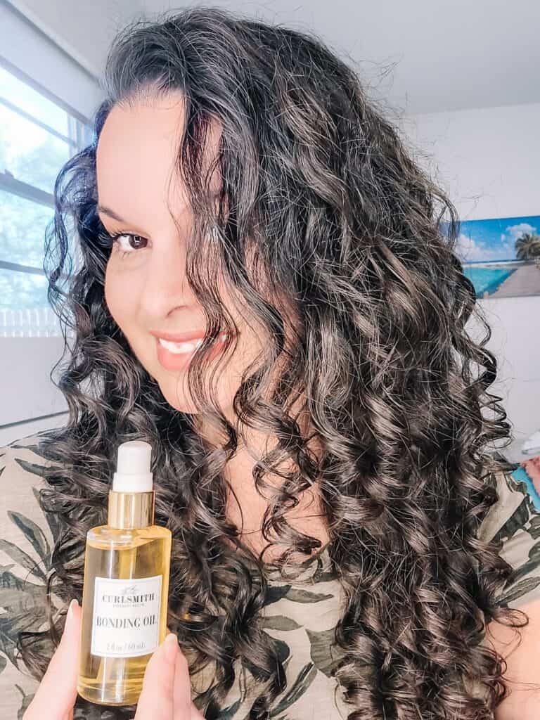 Curlsmith Bonding Oil review - holding up bottle of Curlsmith Bonding Oil in front of curly hair