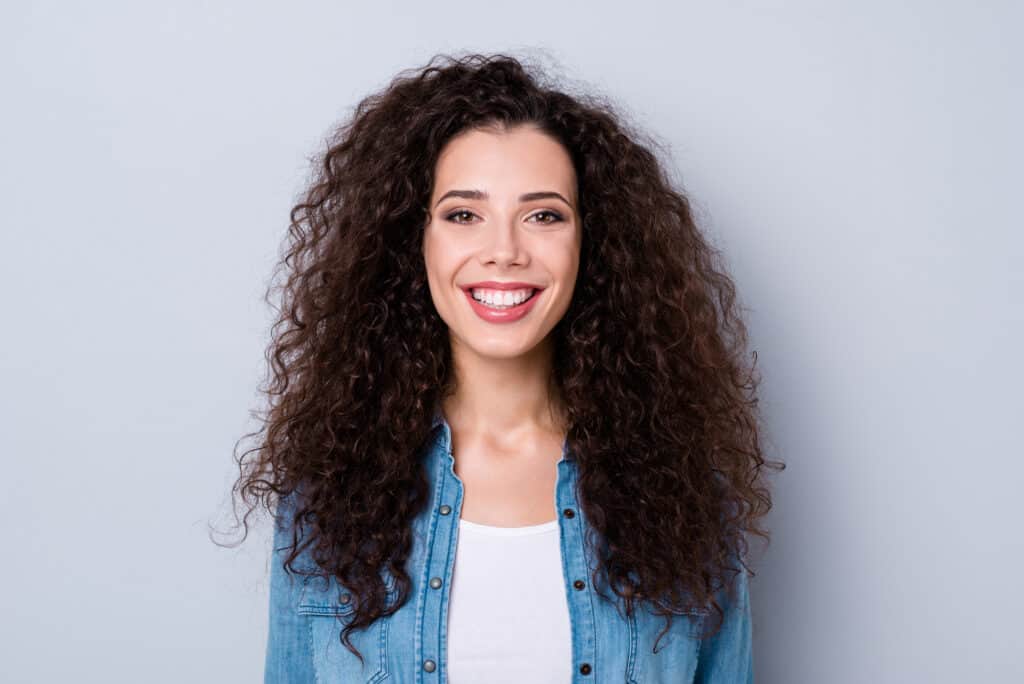 woman smiling facing the camera with long curly hair who uses the LOC method