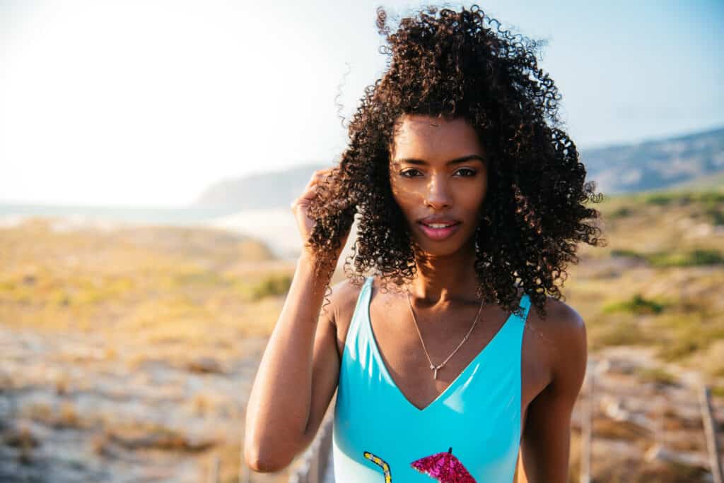 black woman with curly hair at the beach in the summer