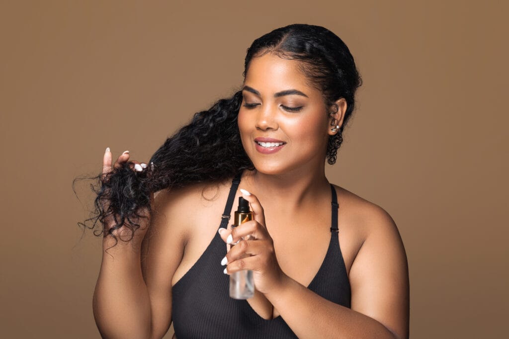 woman applying grapeseed oil to curly hair