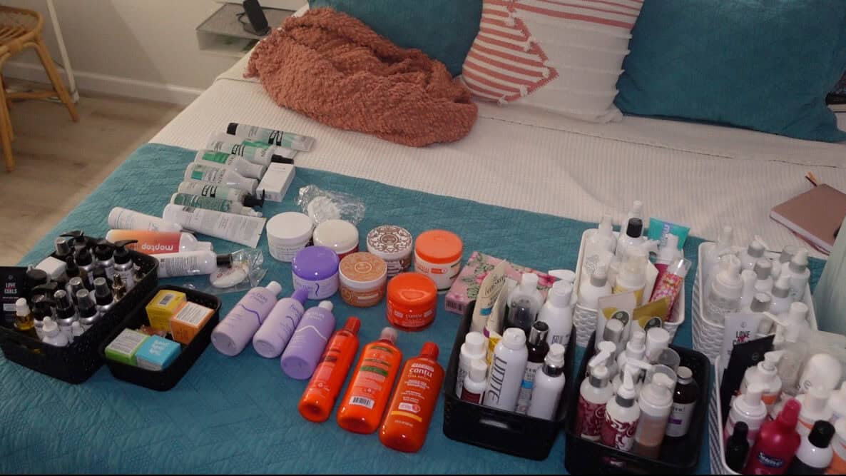 curly hair product stash all on a bed to declutter